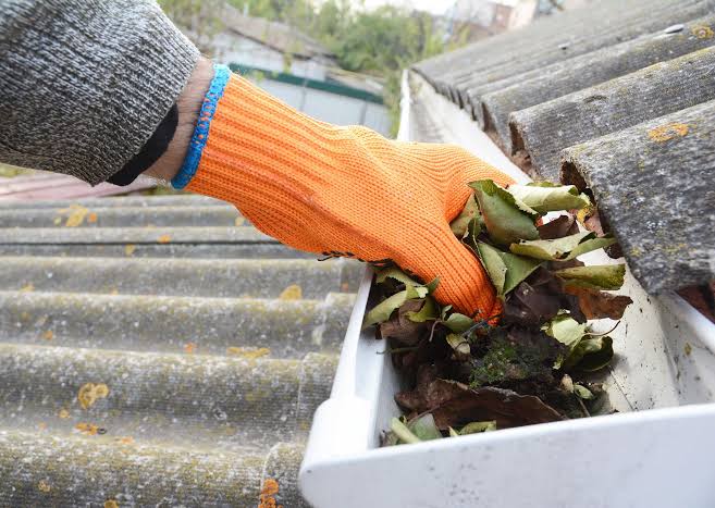 United Roofing & Siding gutter cleaning service removing leaves and debris from residential gutters in Sioux Falls, SD