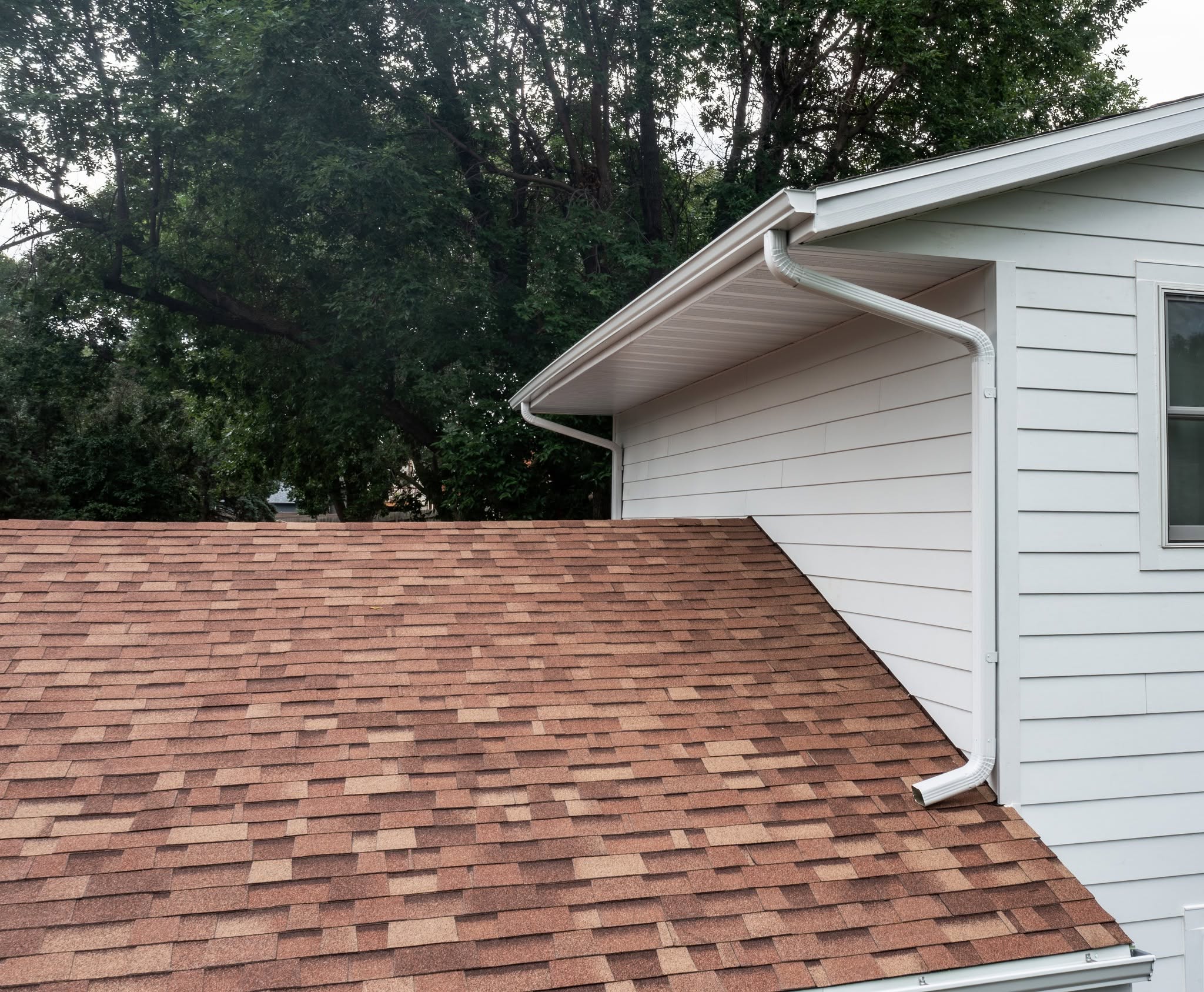 United Roofing & Siding gutter downspout installation with residential shingle roofing in Sioux Falls, SD